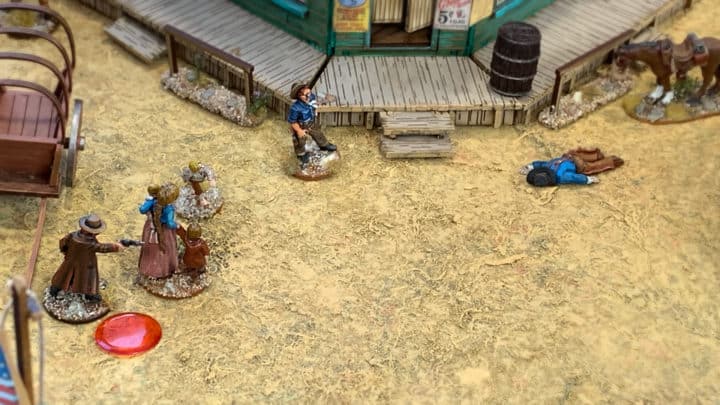 Shootout zwischen Cowboy und Bandit. Der Cowboy versteckt sich hinter Zivilisten. Vor dem Saloon liegt der getroffener Bandit auf dem Boden.